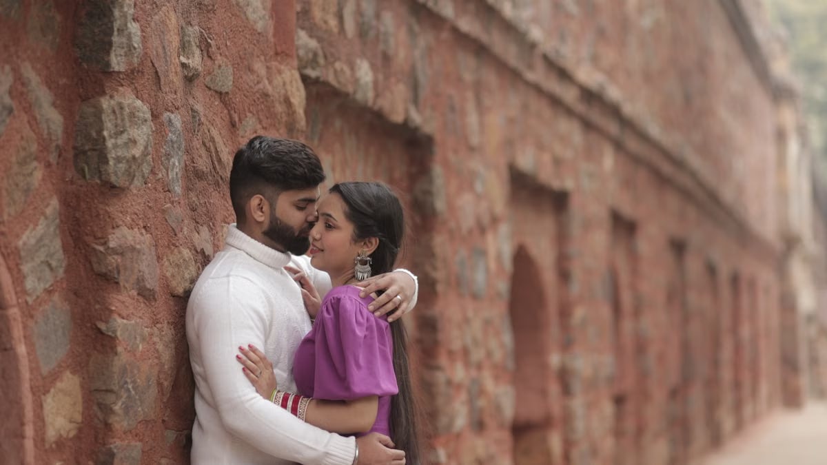 Romantic couple embracing against an ancient stone wall setting a loving mood.